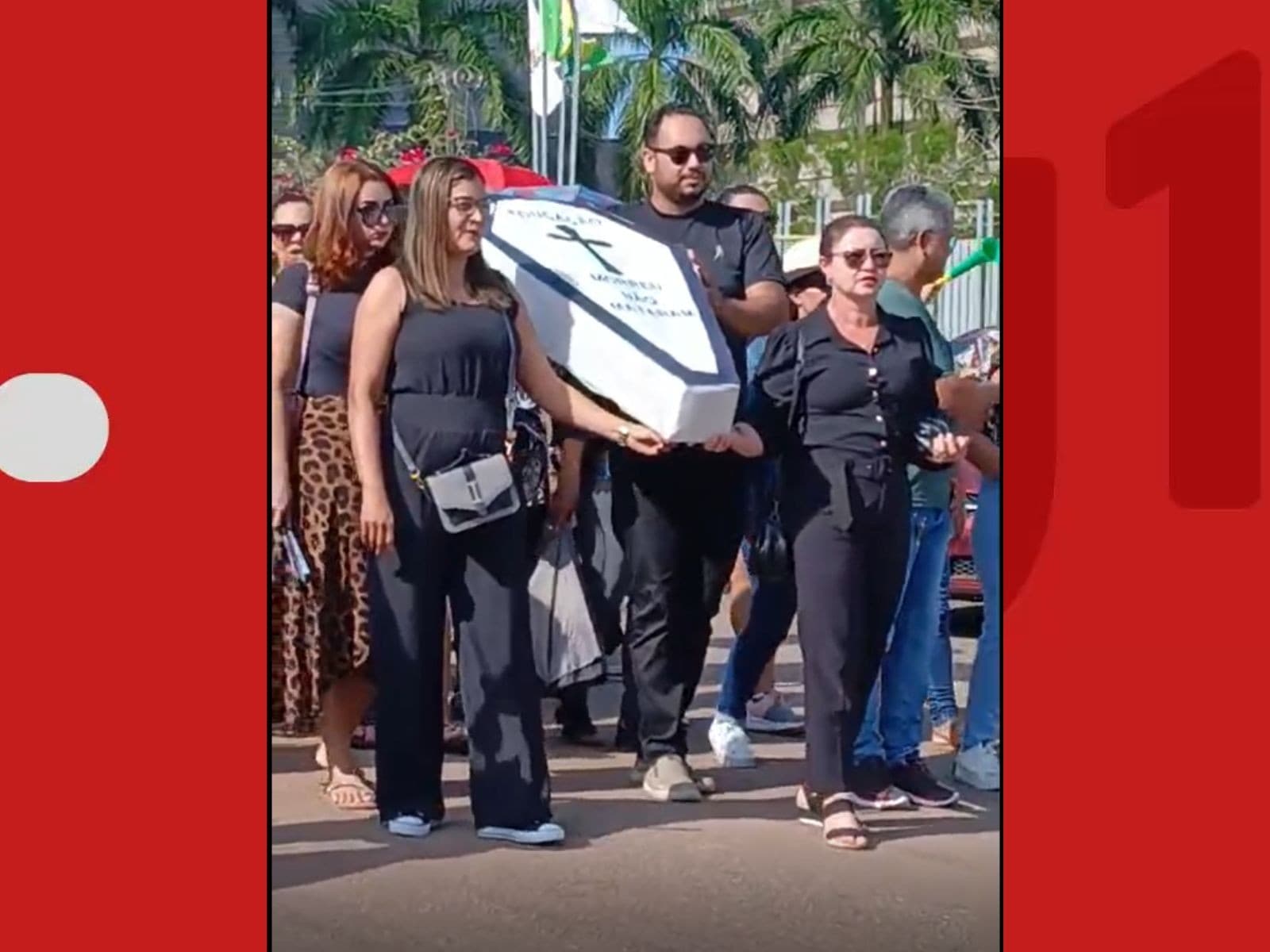Professores vestidos de preto carregam caixão em frente ao Tribunal de Justiça do Acre.