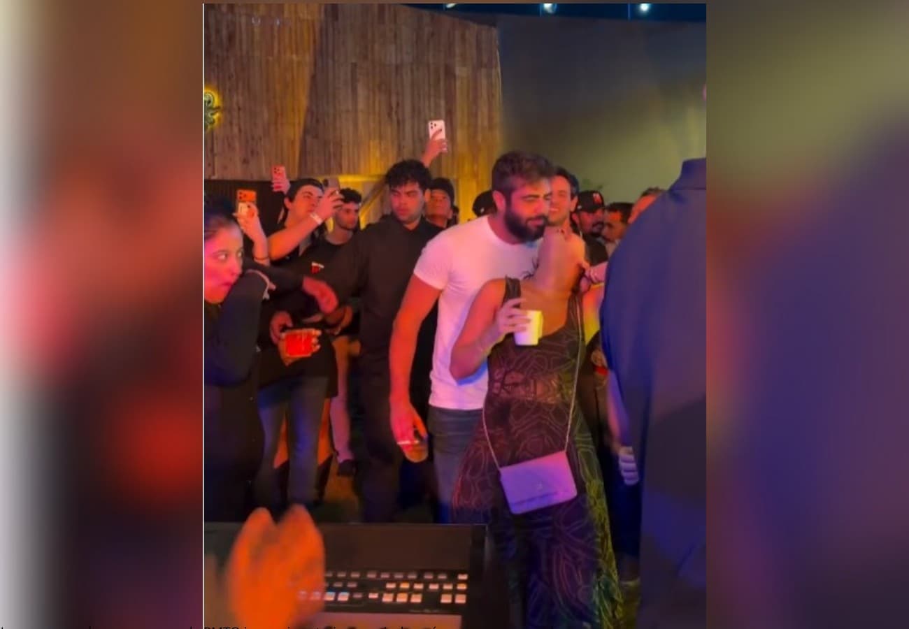Cantor no palco iluminado, próximo a mulher, durante apresentação noturna em Porto Nacional.
