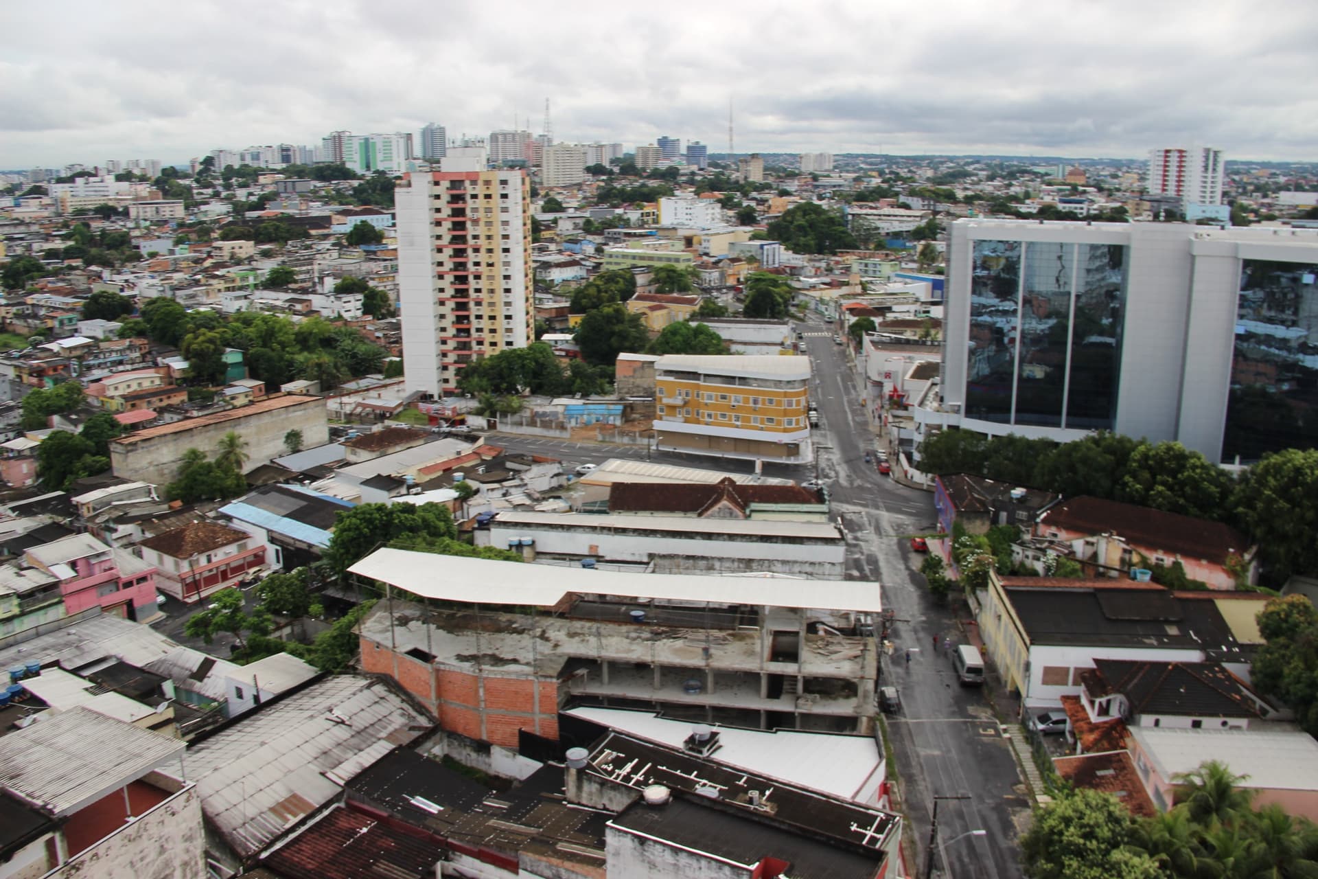 Rua de bairro periférico em Manaus com calçamento irregular e fios elétricos.