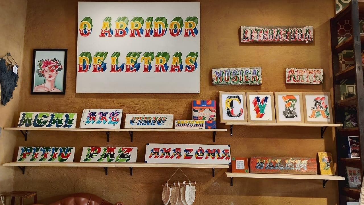 Tipografia colorida pintada em madeira de casco de barco exposta em estande de feira em Belém.