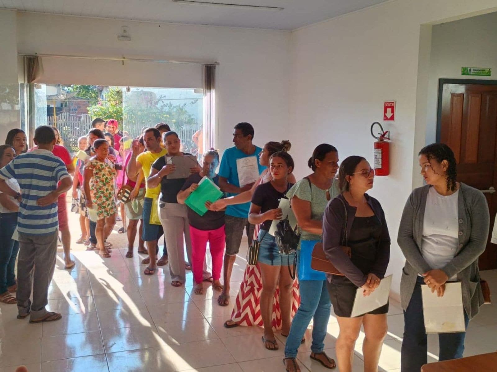 Agente da Polícia Civil entrega documento de identidade para idosa em município do interior do Acre.