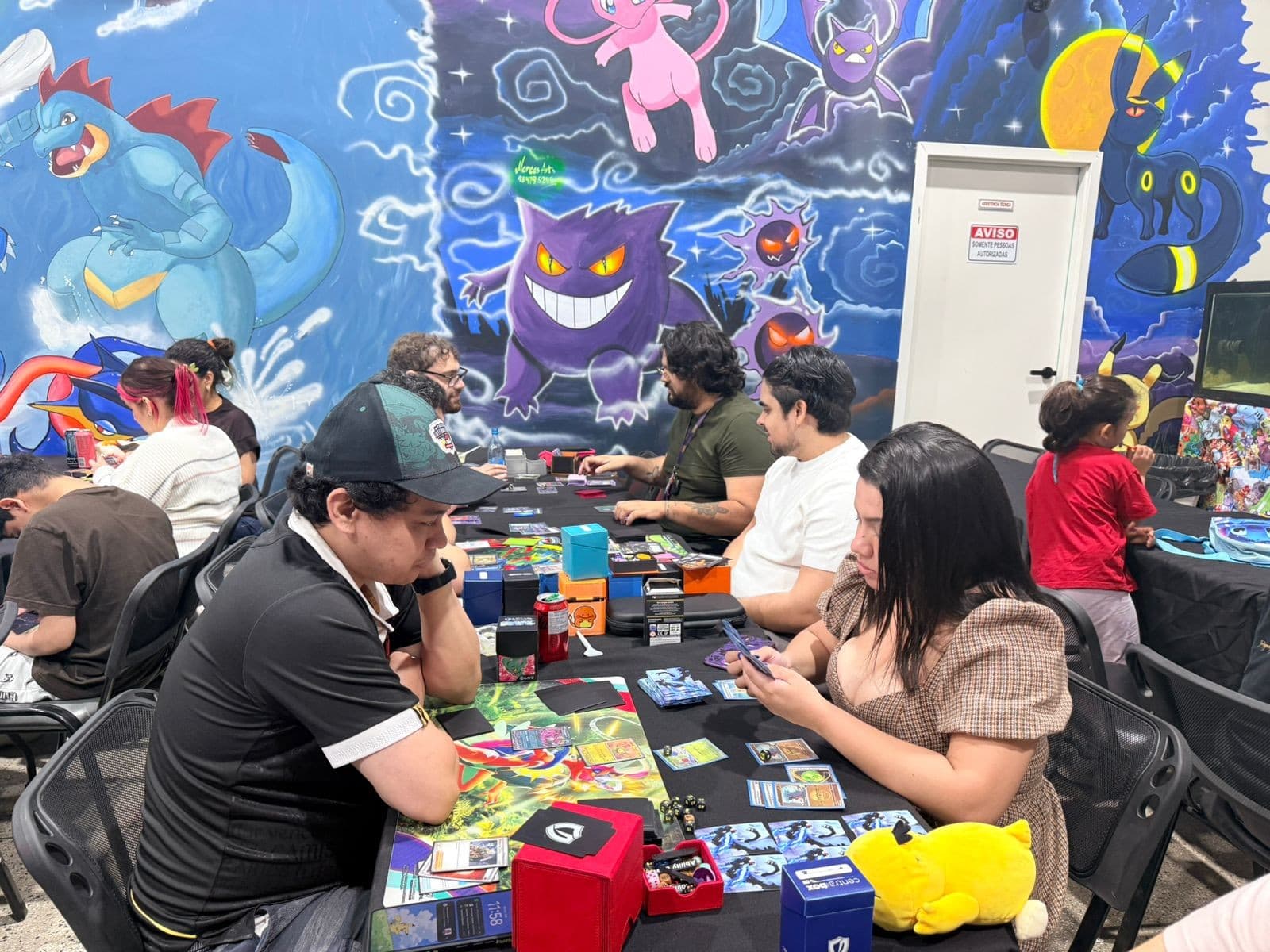 Mesa de jogo coberta por tapete verde com baralhos de cartas colecionáveis dispostos.