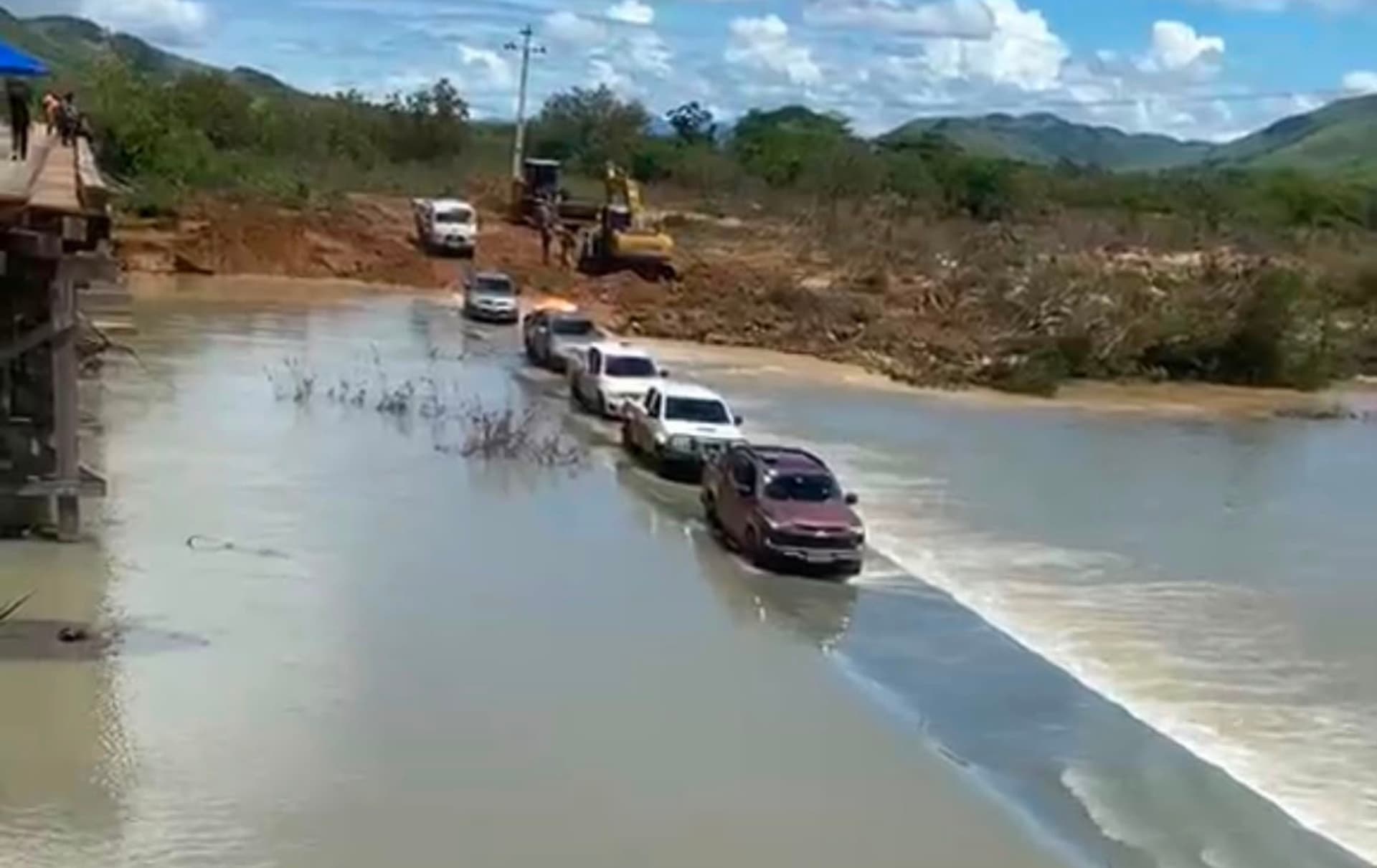 Veículos passam por rota de terra ao lado da estrutura destruída da ponte sobre o igarapé Cambaru.