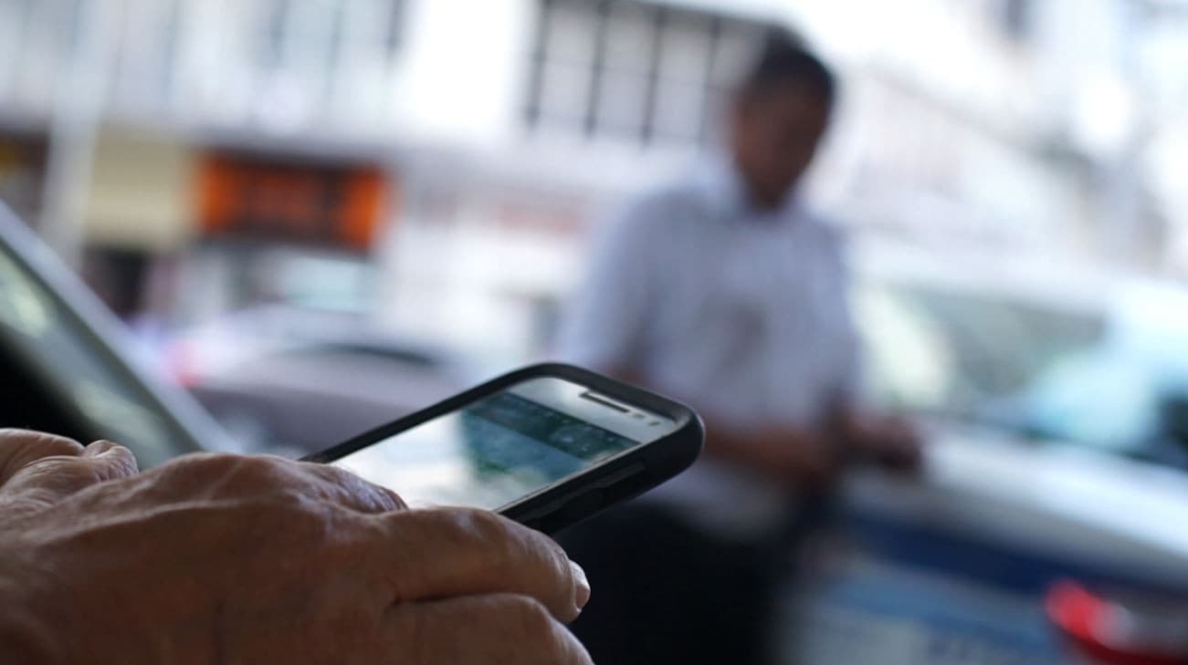 Moradora segura smartphone em comunidade rural do Amapá mostrando tela de aplicativo.