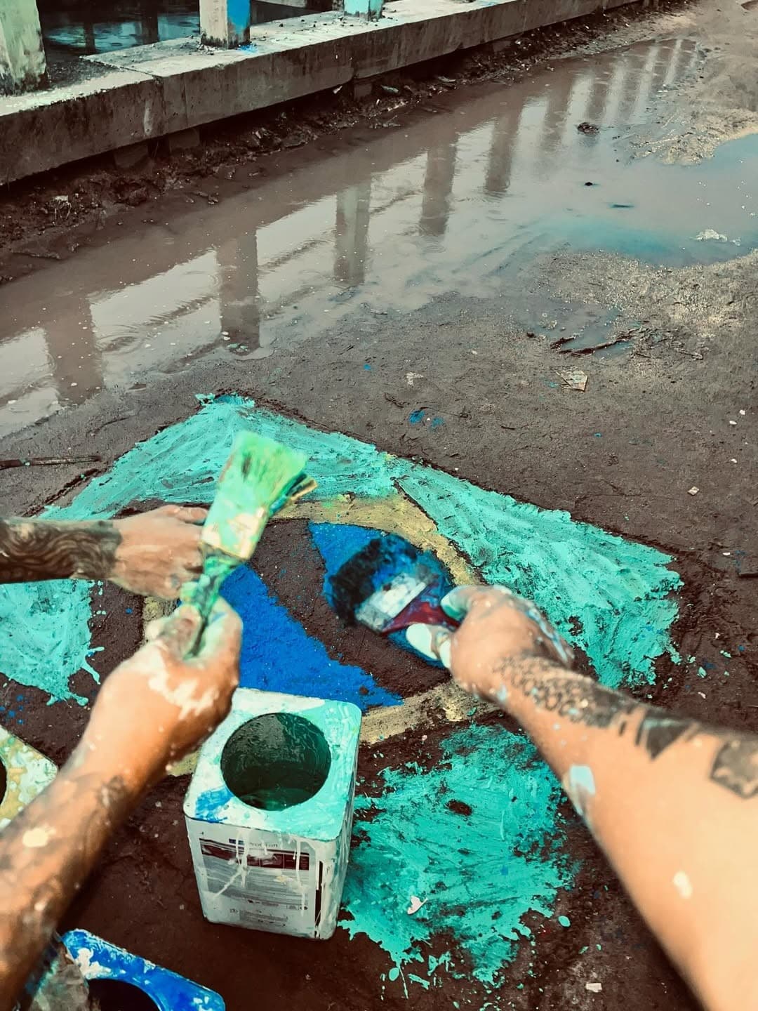 Rua de terra com pinturas da bandeira do Brasil misturadas à lama no bairro do Guamá.