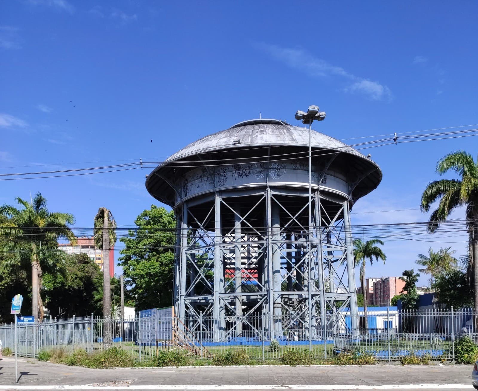 Estrutura de ferro da Caixa D'água de São Brás, em Belém, com pintura descascada e sinais visíveis de corrosão e vegetação invasiva.