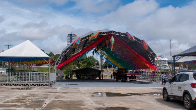 Dançadores de quadrilha junina com figurinos coloridos em praça iluminada de Macapá.