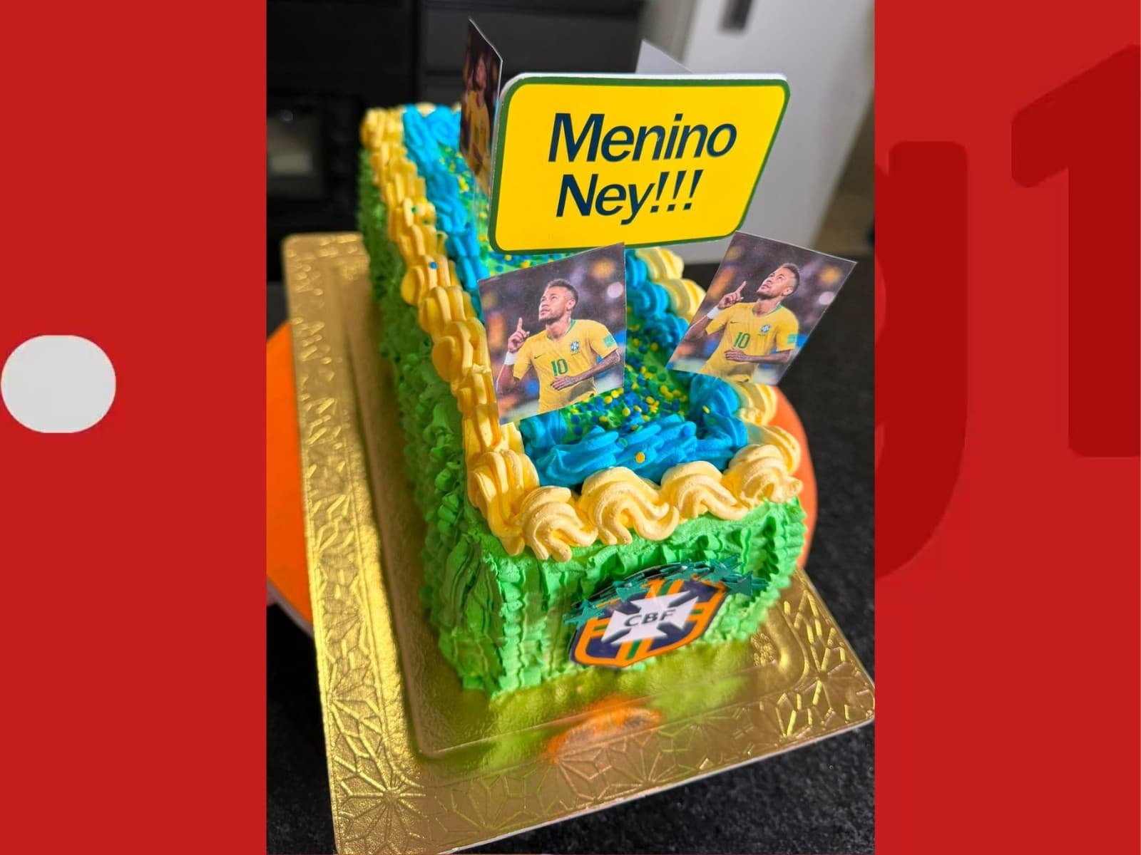 Bolo decorado com as cores do Brasil e foto de jogador exposto em bancada.