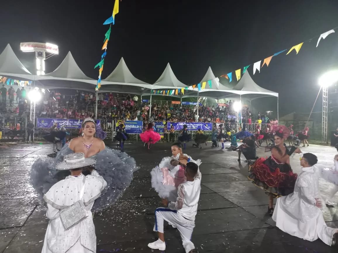 Bailarinos de quadrilha junina com vestidos coloridos ensaiam sob luzes de palco em Porto Velho.