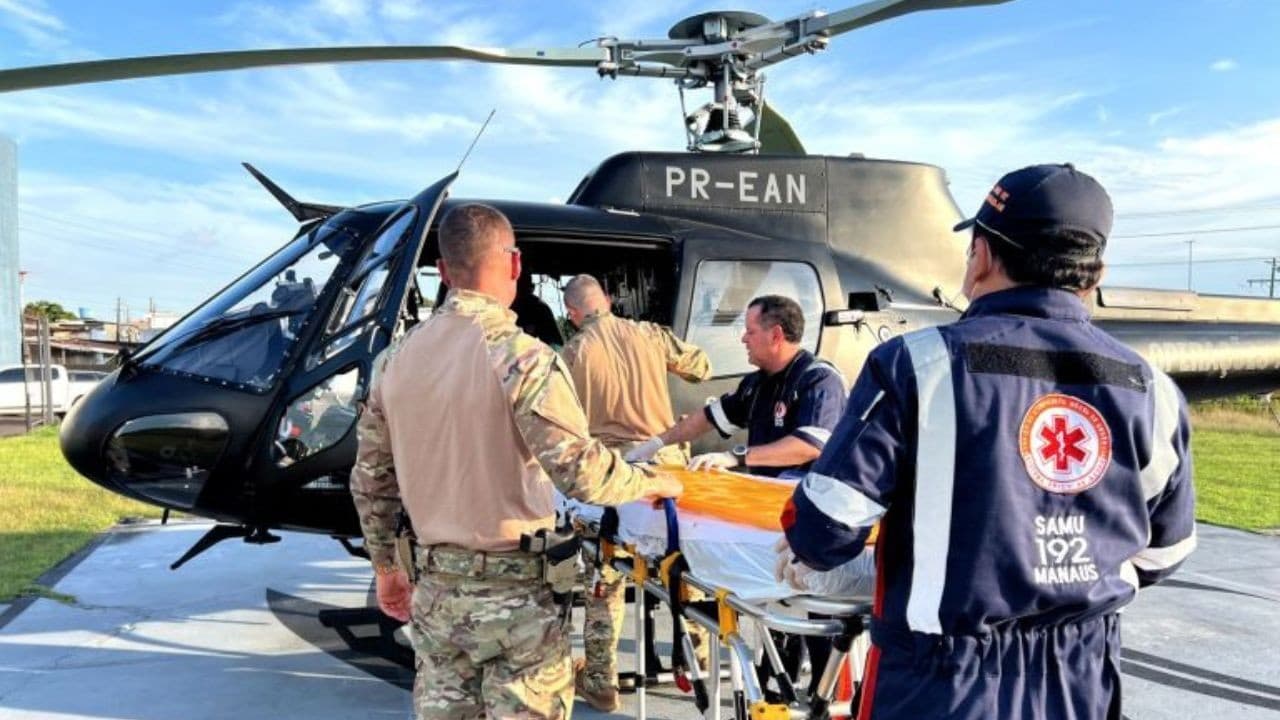 Helicóptero da SSP-AM pousa em área de terra batida durante operação de resgate em comunidade rural.
