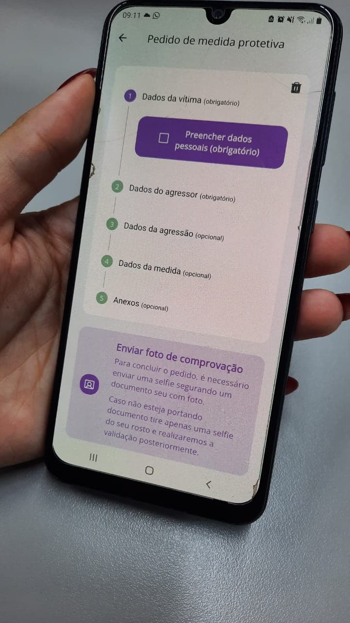 Mulher utiliza smartphone para acessar aplicativo de medidas protetivas em ambiente público.