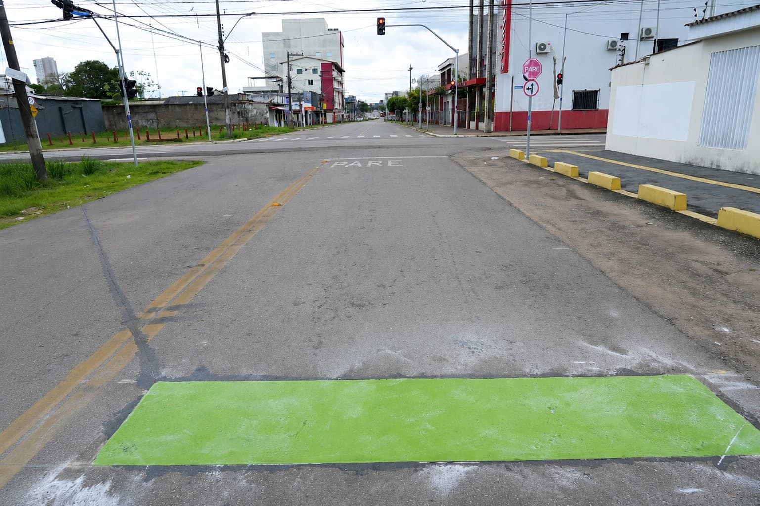 Faixa de asfalto pintada de verde em cruzamento de Porto Velho indica ponto de parada para sensores de trânsito.