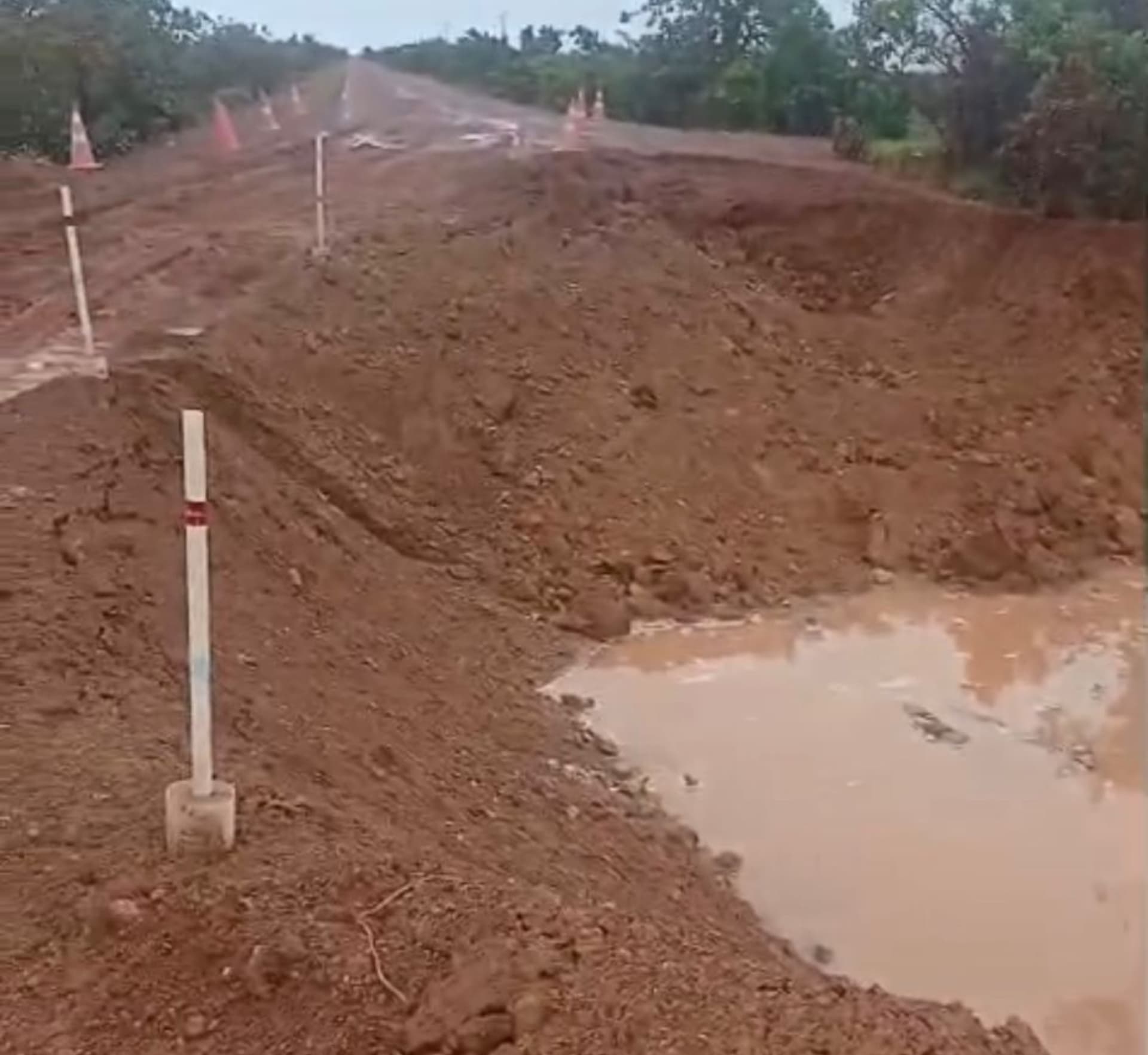 Trecho destruído da BR-401 em Roraima com cratera aberta ao lado de um desvio de terra.