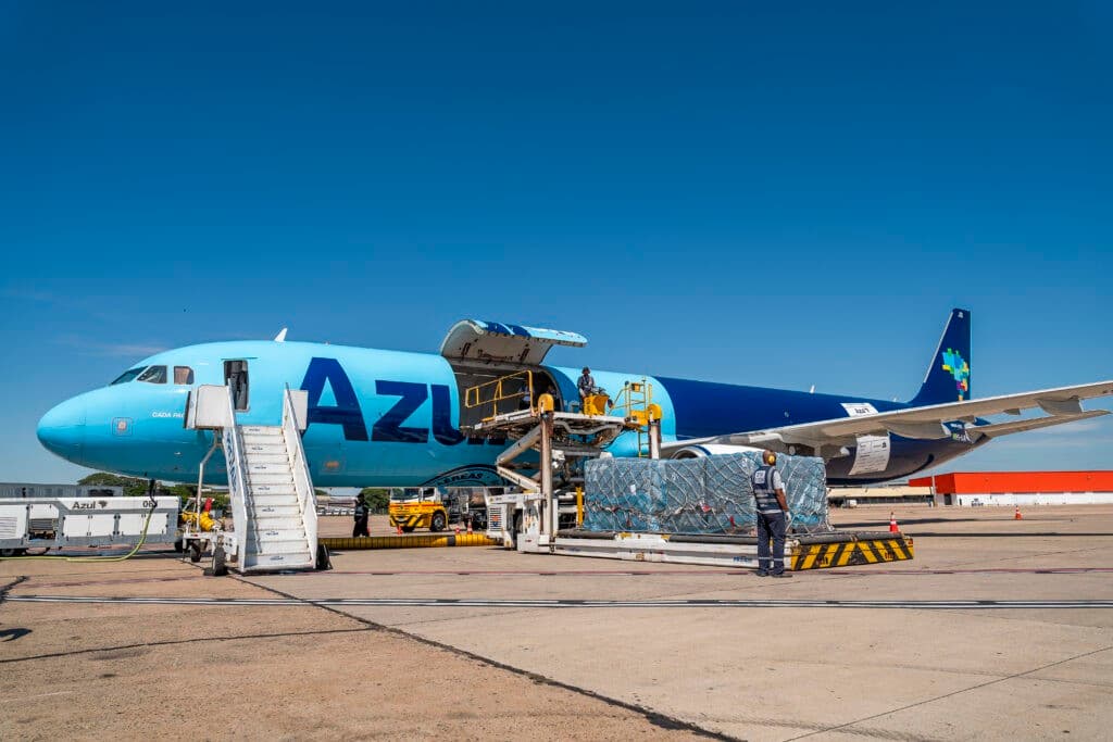 Avião cargueiro da Azul em pista de pouso com caixas de transporte no pátio.