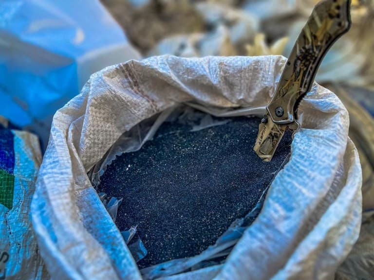 Caminhão com semirreboque parado na margem da BR-319 com sacos de minério ao lado durante fiscalização.