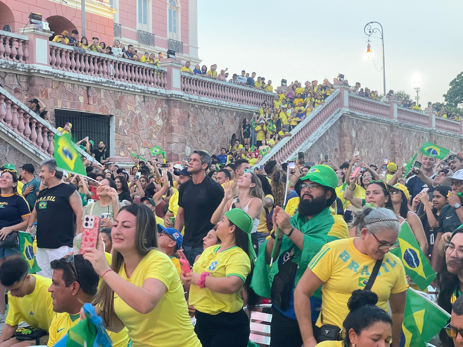 Torcedores cantam e dançam em frente a telão montado em via pública do Centro de Manaus durante evento cultural.