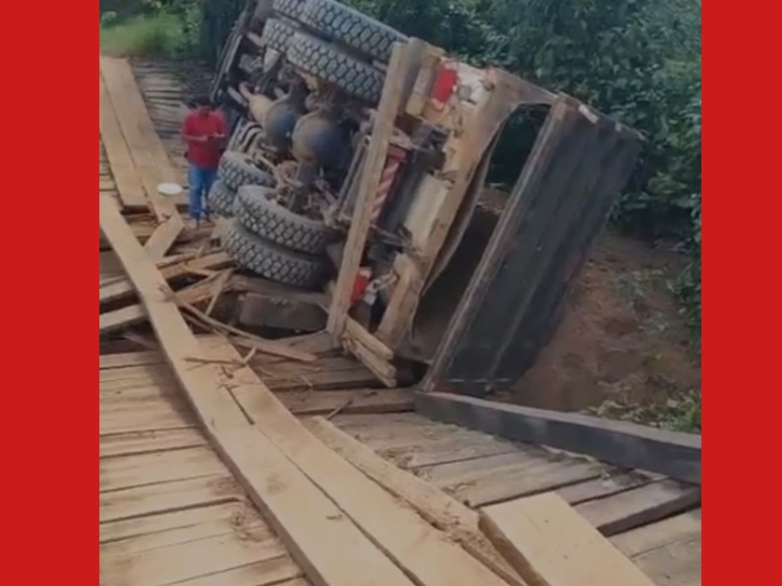 Ponte de madeira destruída com caminhão preso no barranco