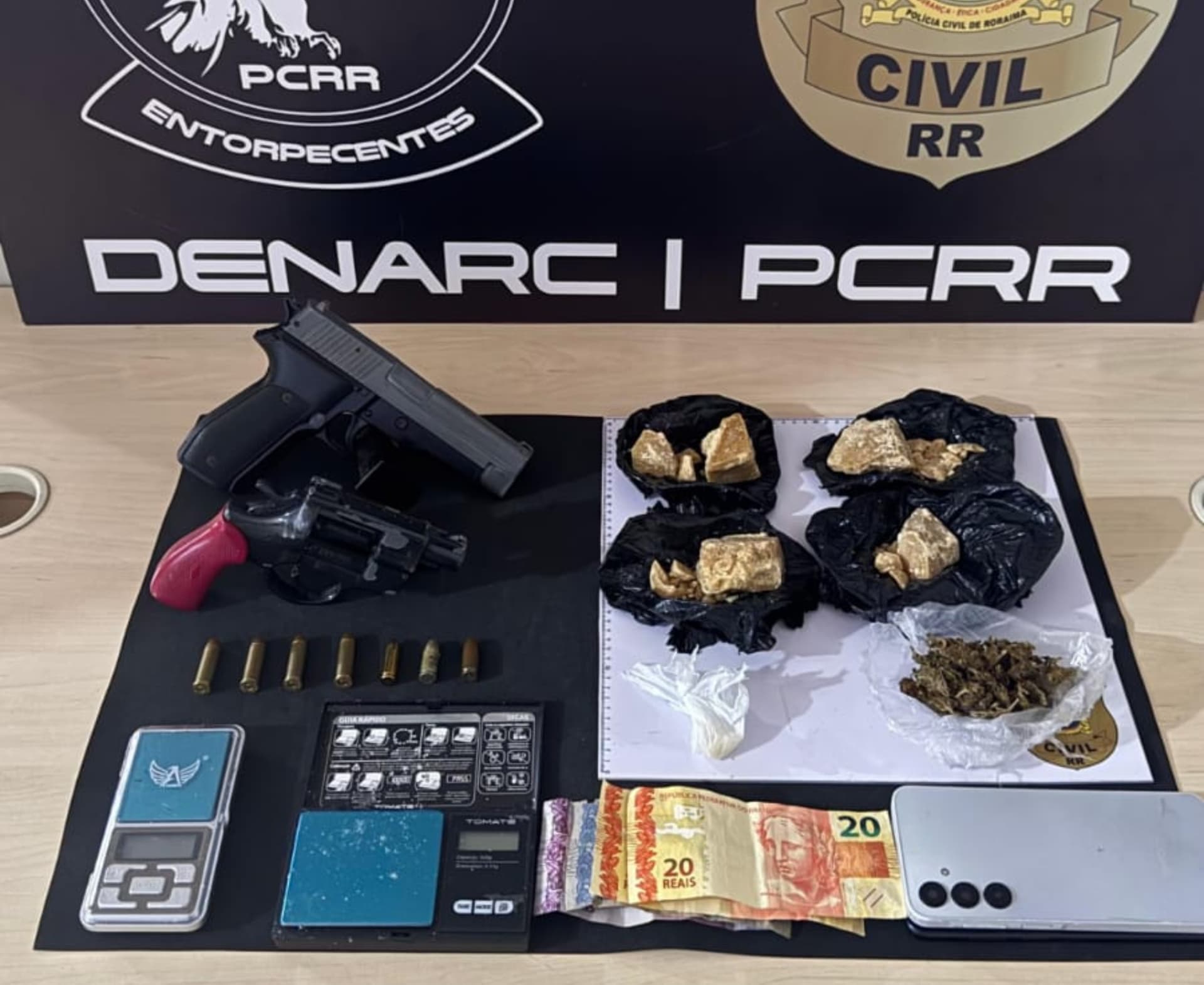 Material apreendido pela Polícia Civil, incluindo drogas e arma, sobre mesa durante ação em Boa Vista.