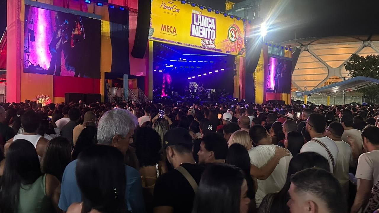 Palco iluminado com luzes roxas e azuis no Sambódromo de Manaus durante show de pagode com público lotado.