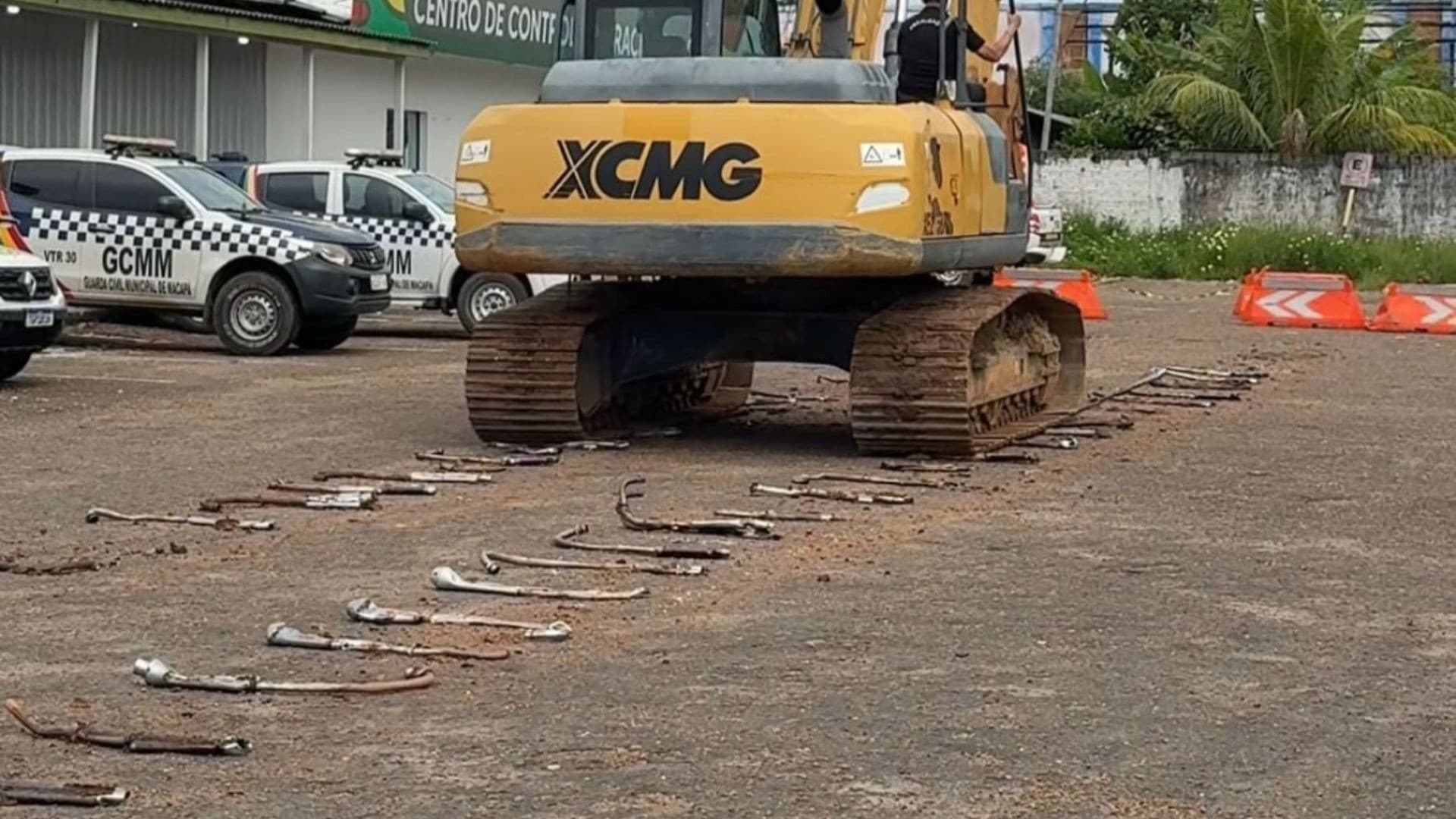 Pilha de escapamentos de motos espalhados no chão de pátio da CTMac antes de serem triturados por máquina pesada.