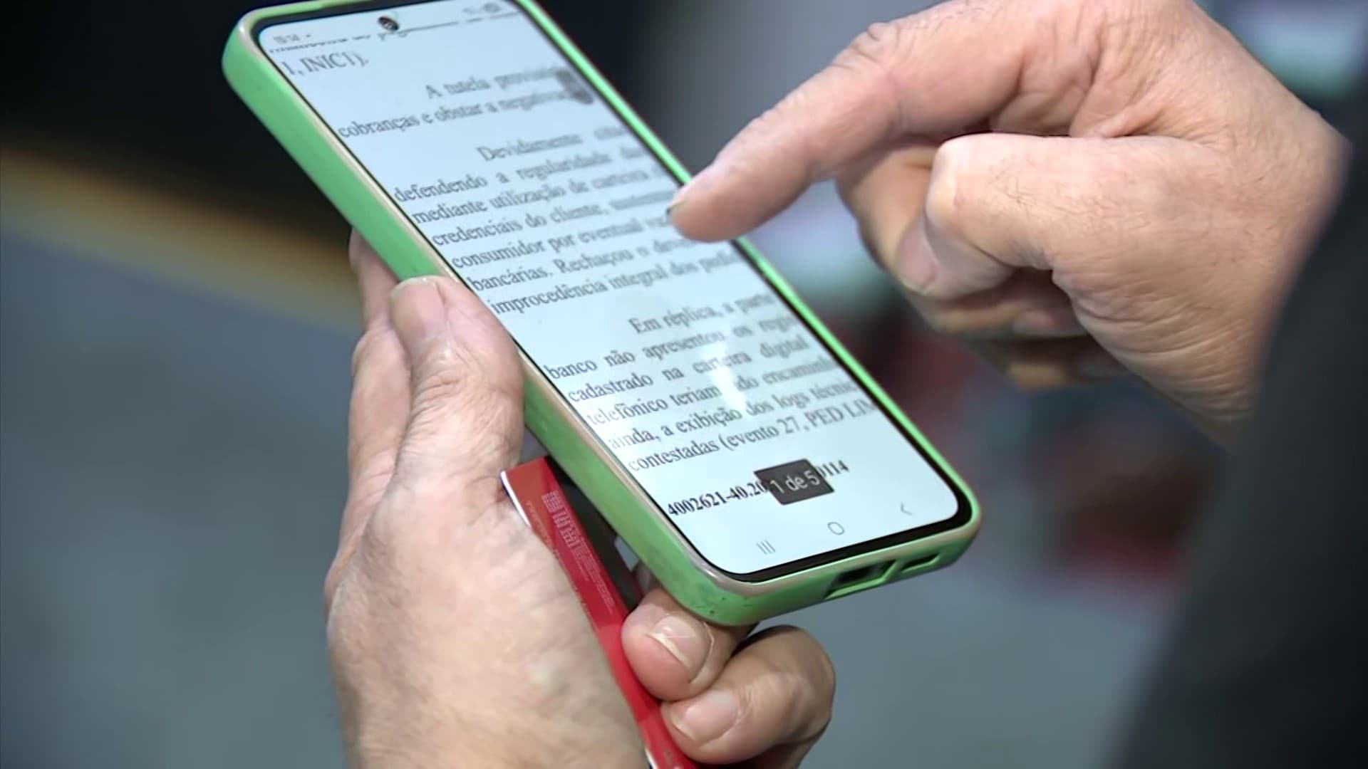 Pessoa segura o celular enquanto visualiza aplicativo bancário em ambiente urbano.