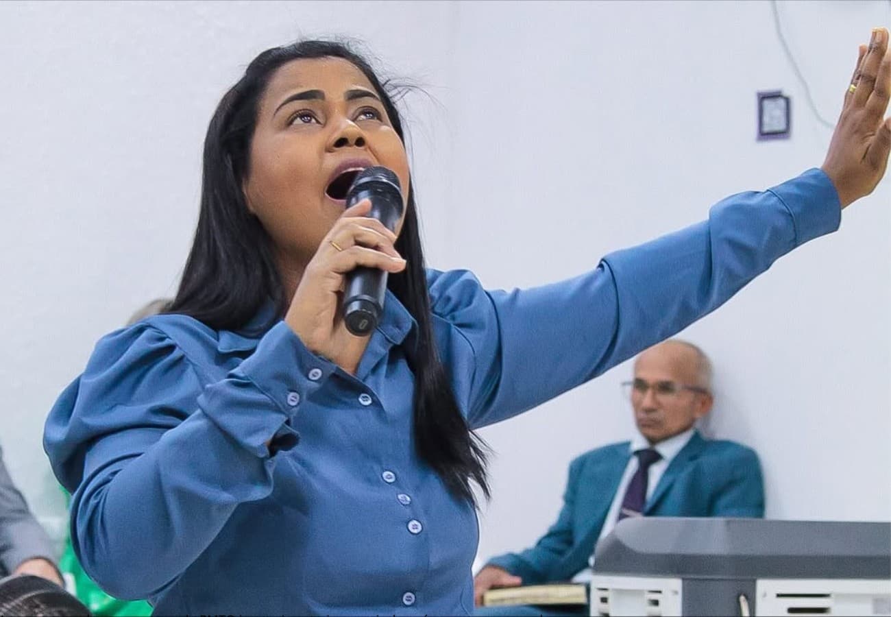Cantora Ana Clézia segura microfone durante apresentação em palco iluminado em igreja de Palmas.