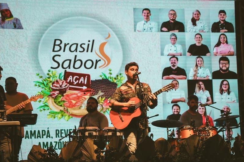Prato com peixe regional servido em festival ao ar livre noturno.