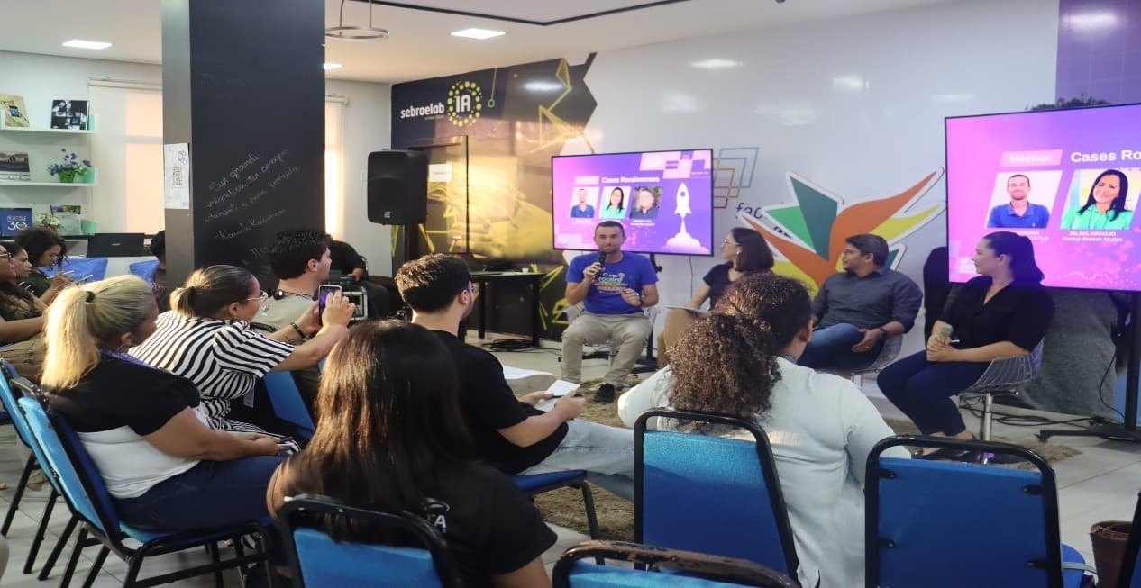 Reunião de empreendedores em sala de escritório com material de apoio espalhado sobre mesa.