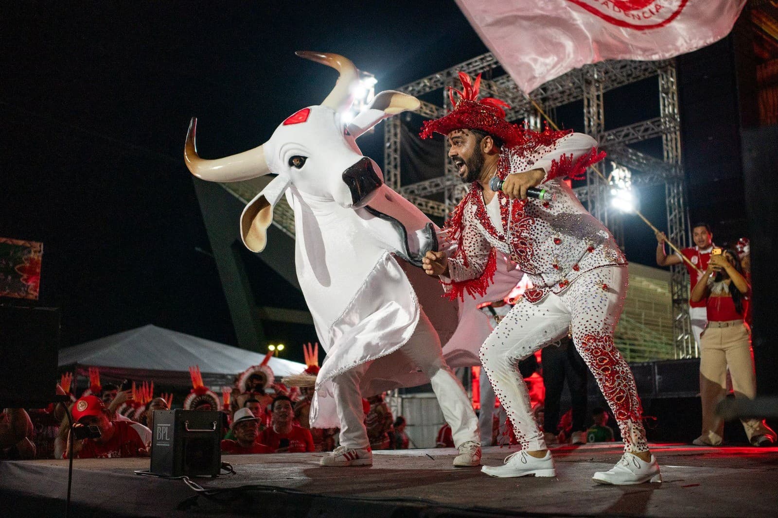 Multidão vestida de vermelho e branco dança no Sambódromo de Manaus durante o último Curral do Boi Garantido.