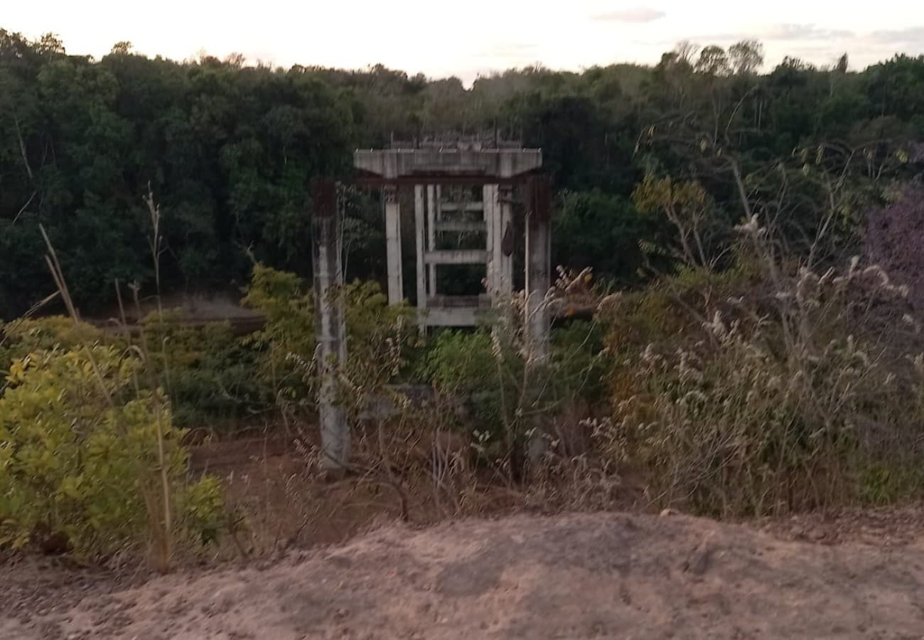 Estrutura de concreto e vergalhões enferrujados de ponte inacabada no meio da vegetação em Rio Sono, Tocantins.
